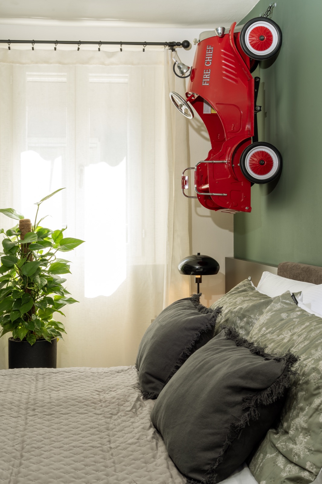 The bed in the Hombre Suite with its cushions and the plant by the window