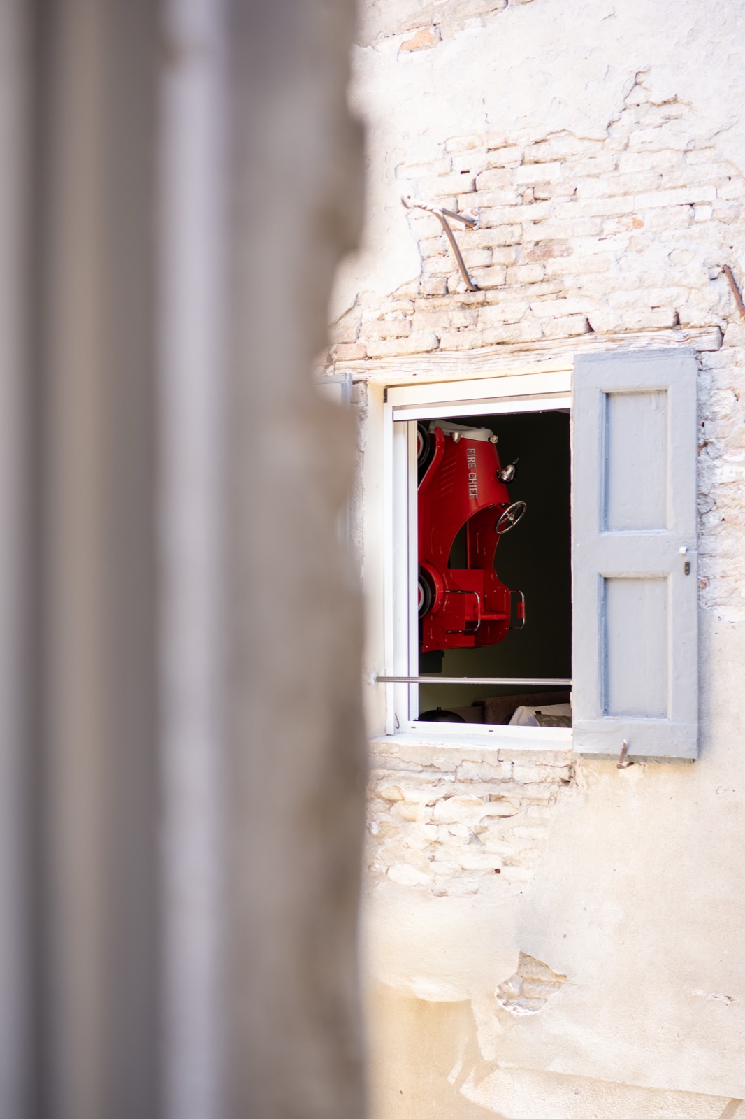 The window onto the courtyard, with the red tin car seen from the room