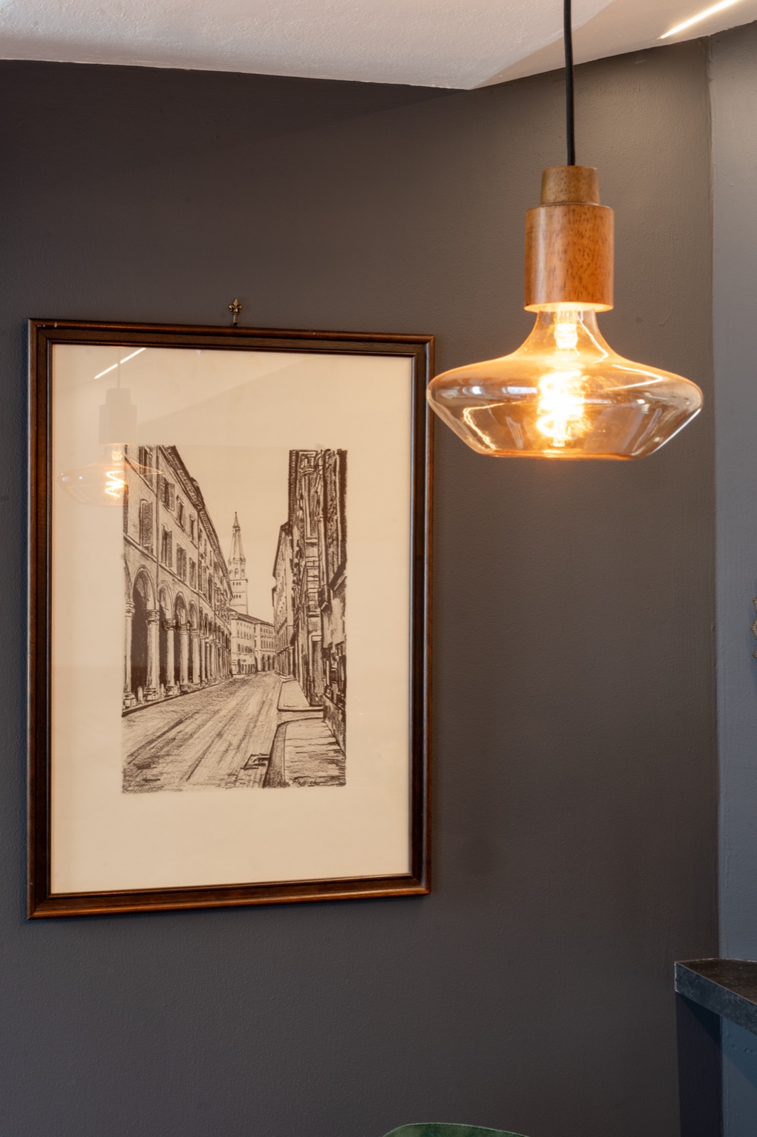 A print of Modena's porticoes beside the pendant lamp