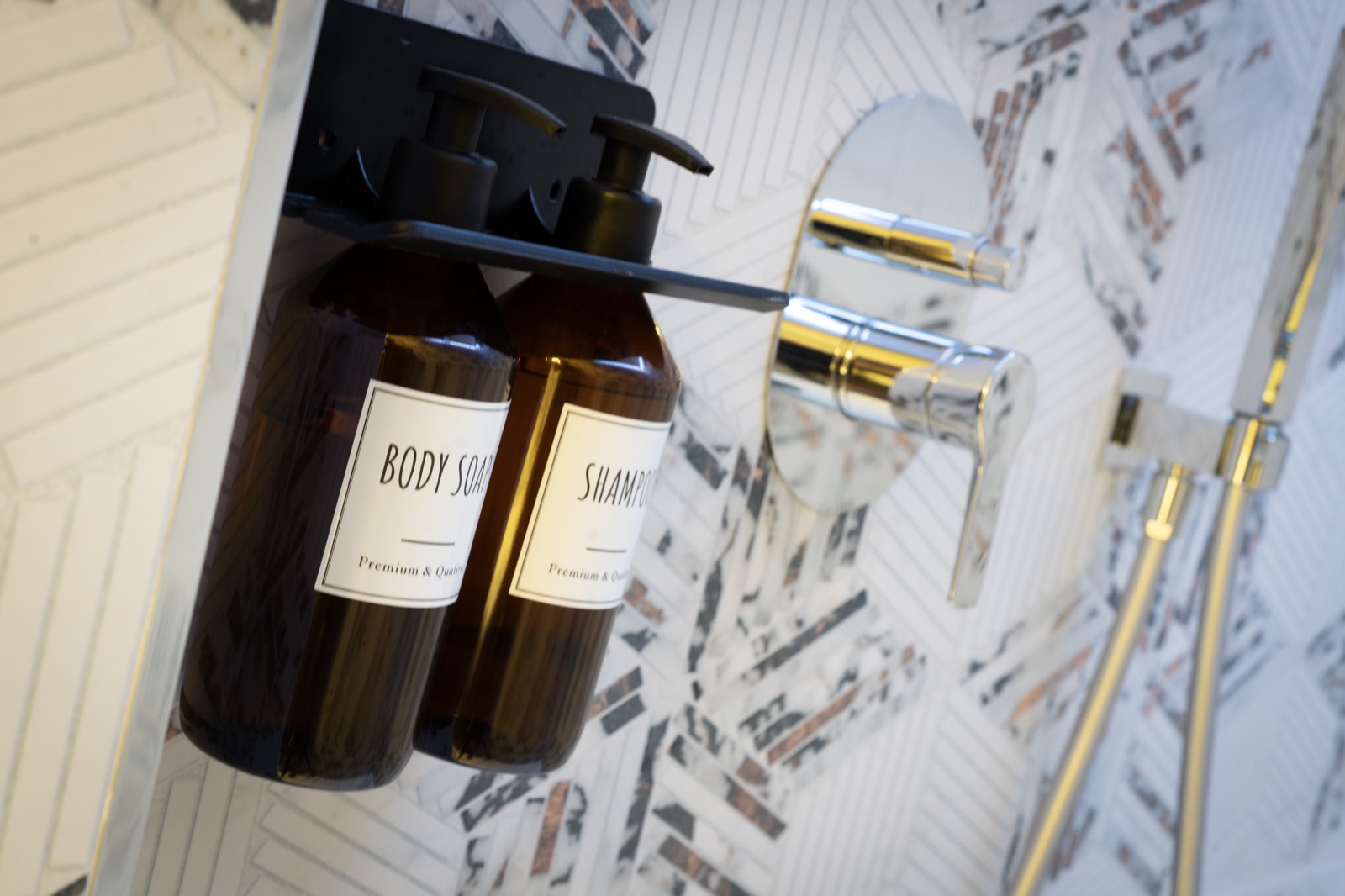 Il dettaglio del rubinetto dorato e dei dispenser di sapone e shampoo