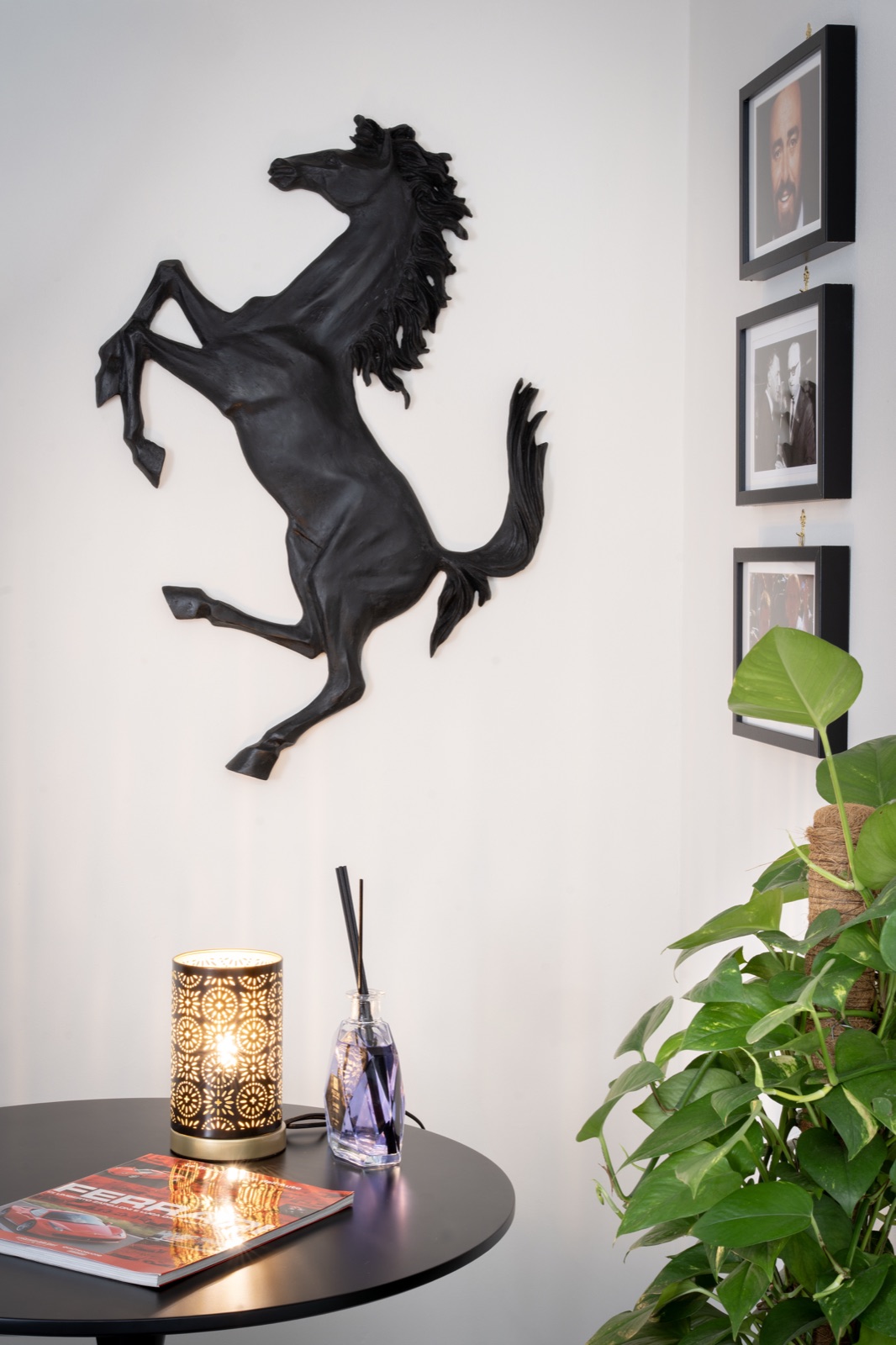 The prancing horse above the side table with the lamp and the diffuser