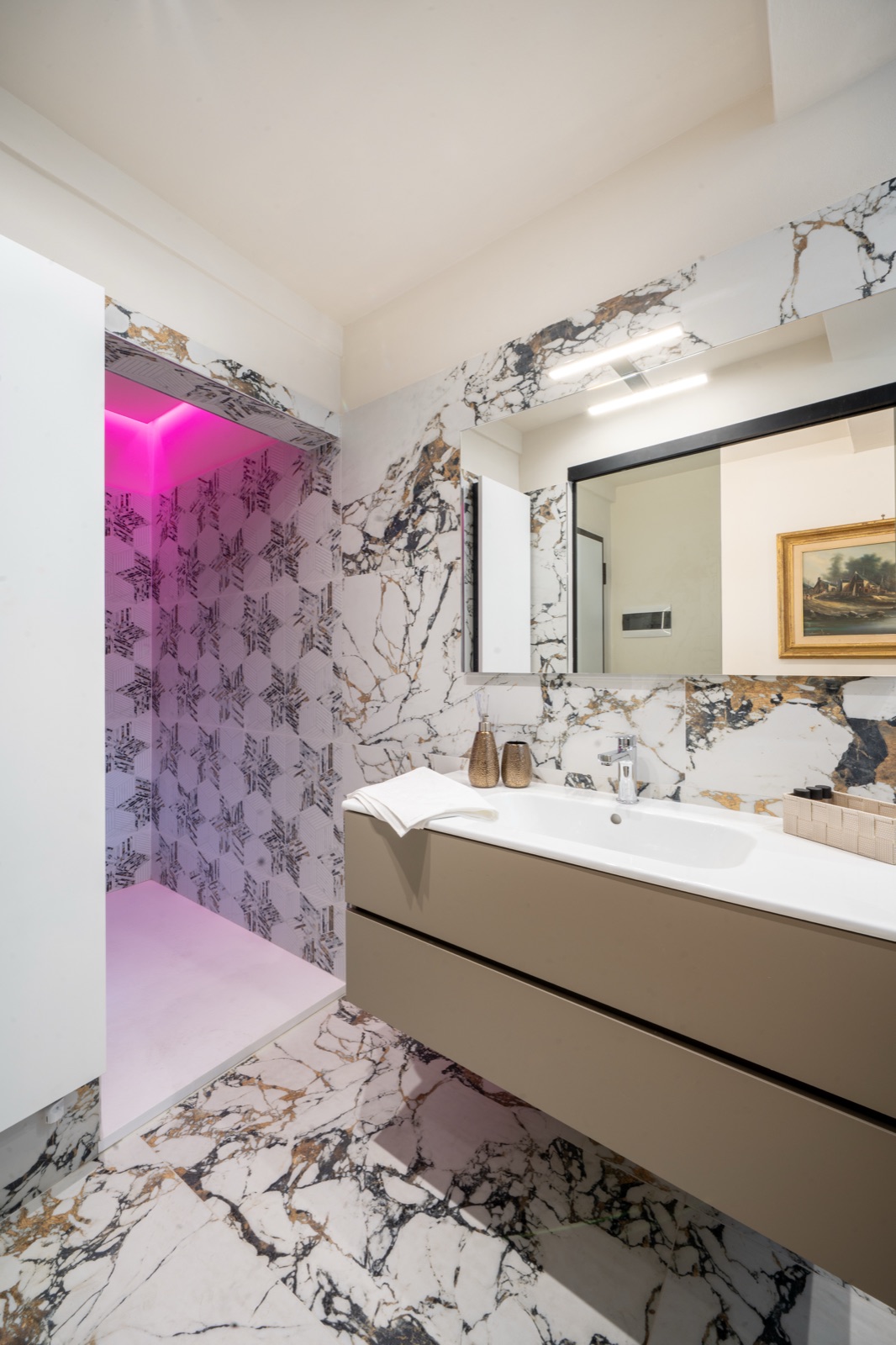 Il bagno in marmo con la doccia walk-in e la cromoterapia accesa