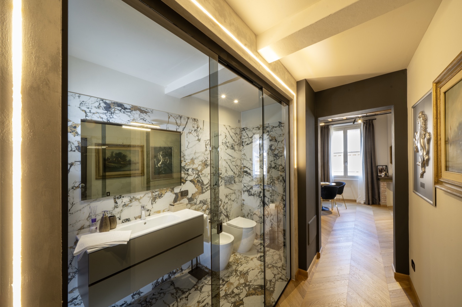 Il bagno in marmo dietro la vetrata, visto dalla camera
