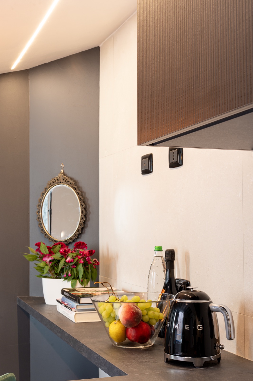 The kitchen counter with fruit, the kettle and the oval mirror