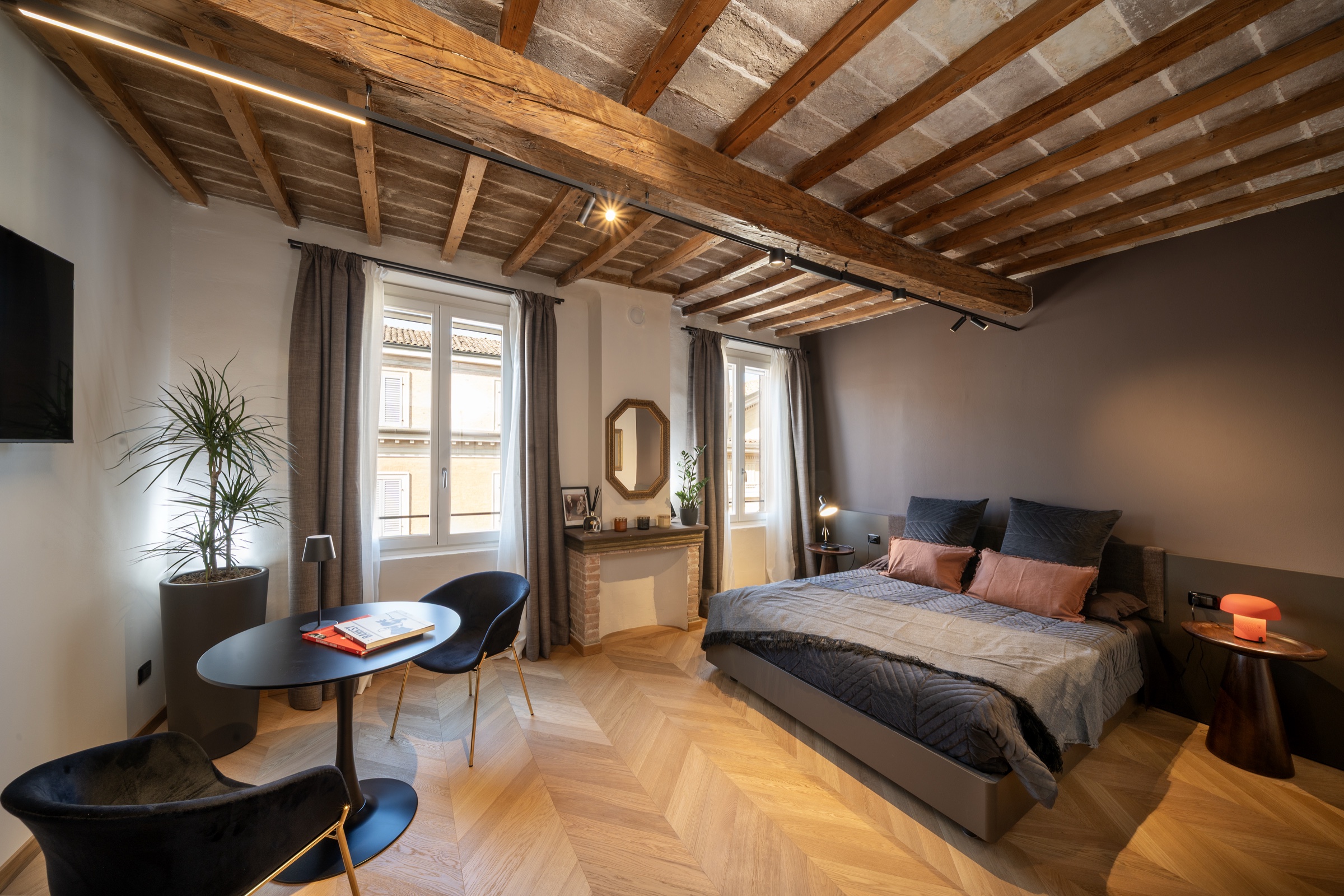 The Allegro Suite bedroom with herringbone parquet and a beamed ceiling