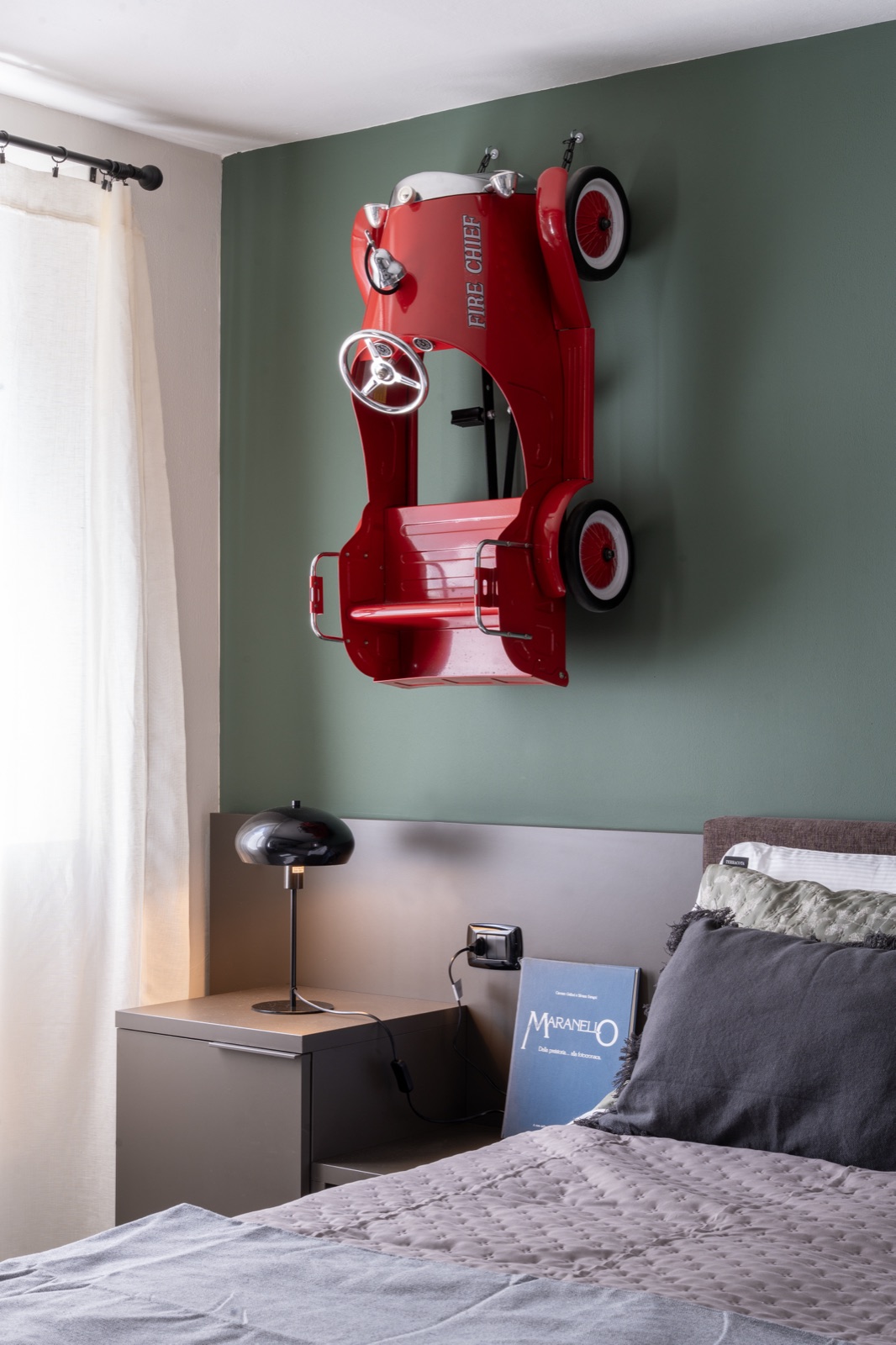 The tin fire engine hanging above the bedside table, next to the bed