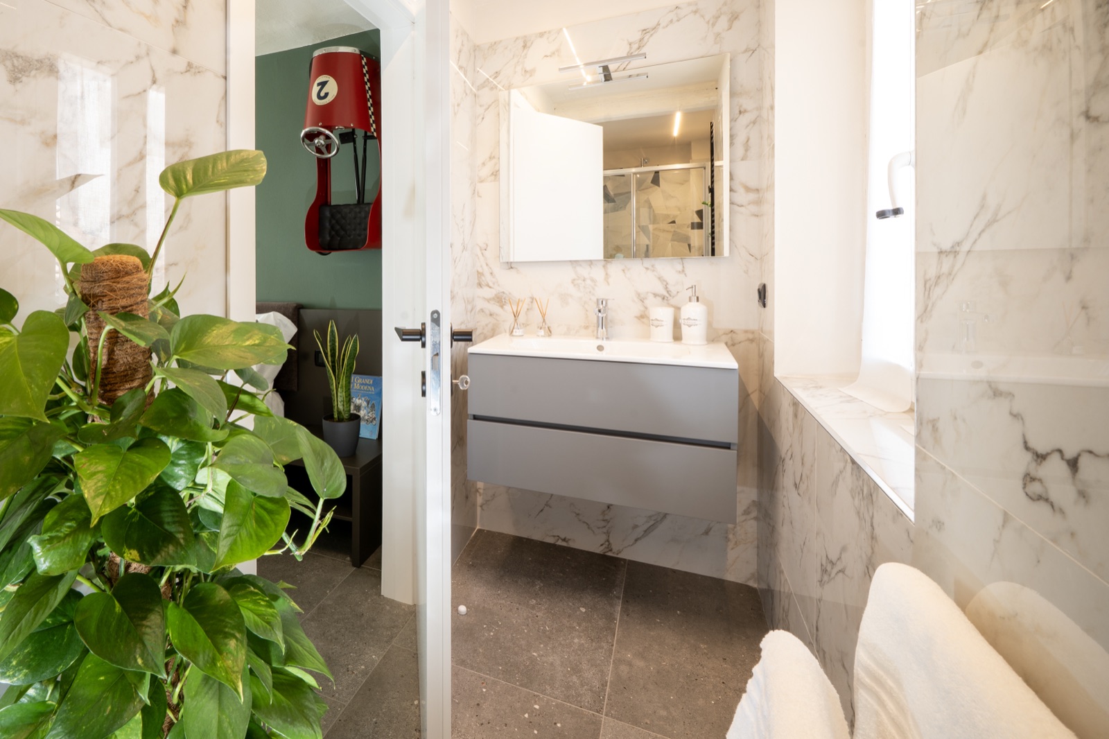 The private bathroom with the wall-hung washbasin and the door open onto the bedroom
